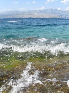 Wellen im Meer mit einem Hintergrund aus felsigen Bergen